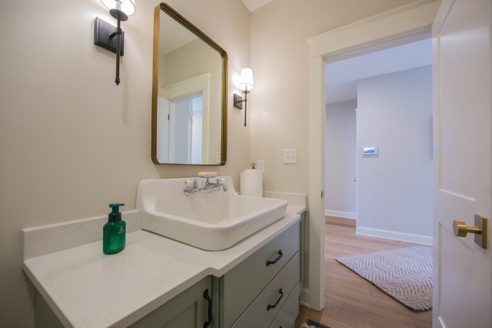 Medium sized traditional cloakroom in Indianapolis with recessed-panel cabinets, green cabinets, a two-piece toilet, beige walls, medium hardwood flooring, a built-in sink, quartz worktops, brown floors, white worktops and a freestanding vanity unit.