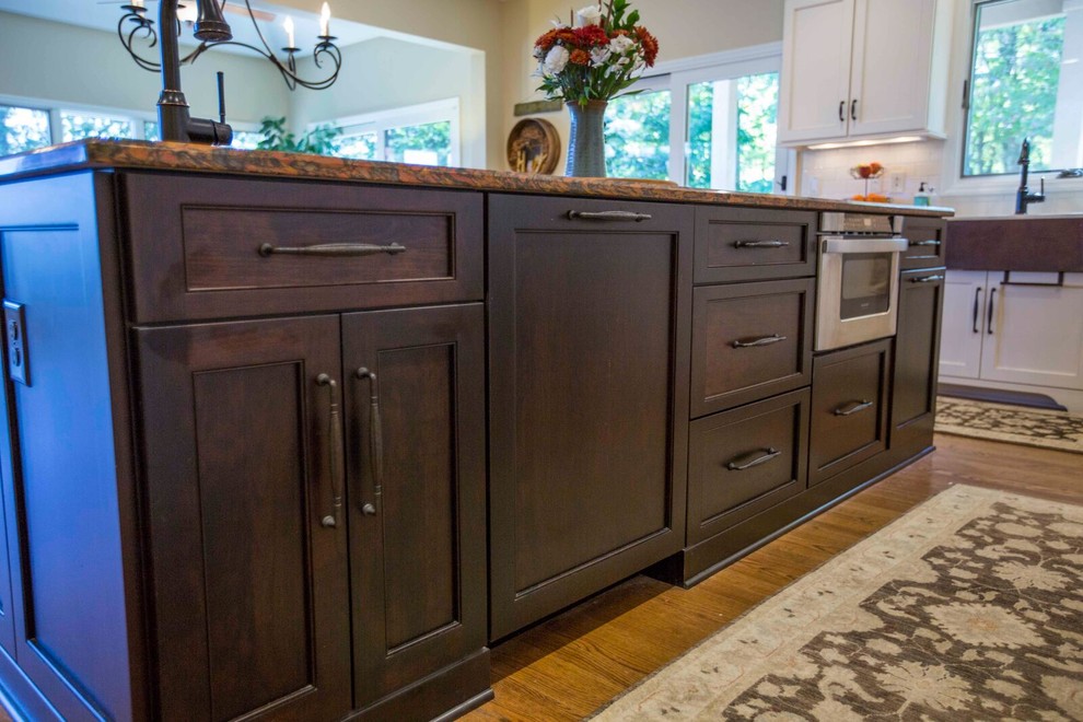 Enclosed kitchen - large transitional l-shaped light wood floor and brown floor enclosed kitchen idea with a farmhouse sink, shaker cabinets, white cabinets, solid surface countertops, white backsplash, porcelain backsplash, stainless steel appliances and an island