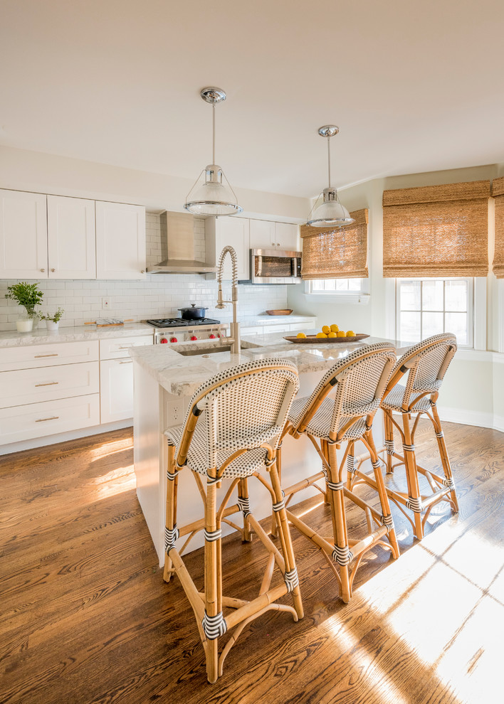 Design ideas for a large transitional l-shaped eat-in kitchen in Philadelphia with an undermount sink, shaker cabinets, white cabinets, stainless steel appliances, with island, white splashback, medium hardwood floors and brown floor.