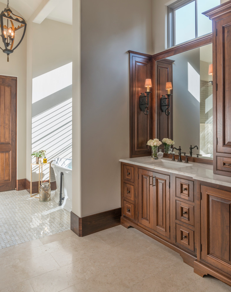 Large mediterranean master bathroom in Atlanta with raised-panel cabinets, medium wood cabinets, a freestanding tub, beige walls, beige tile, white tile, stone tile, travertine floors, an undermount sink and granite benchtops.