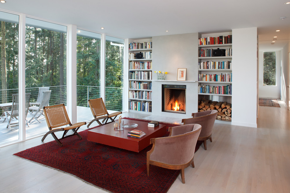 This is an example of a mid-sized contemporary open concept living room in Seattle with a standard fireplace, a plaster fireplace surround, white walls, light hardwood floors and no tv.