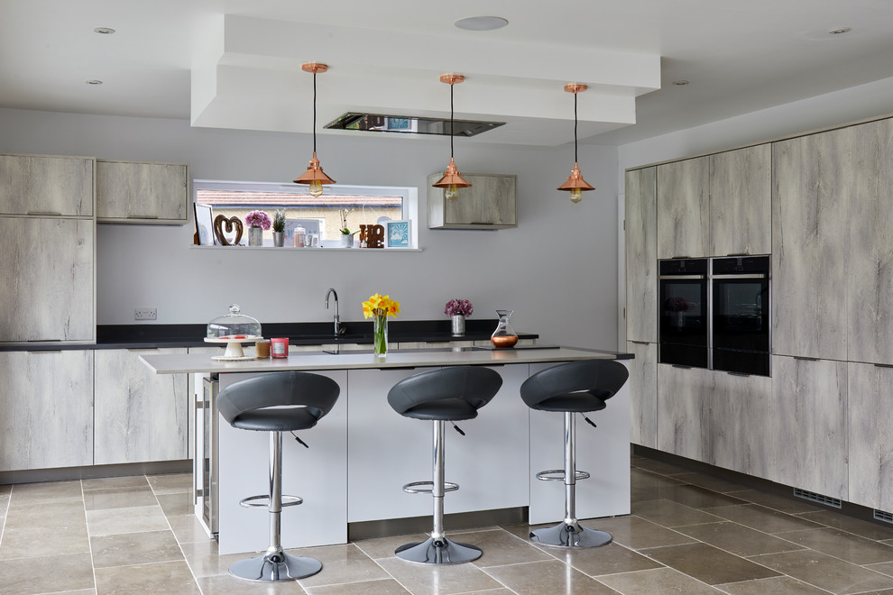 Photo of a large contemporary kitchen in London with flat-panel cabinets, grey cabinets, with island, black appliances, grey floor and black benchtop.