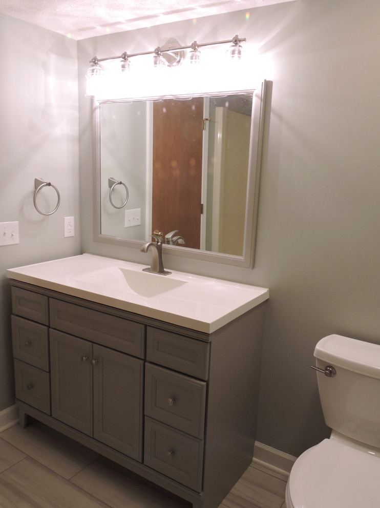 Inspiration for a mid-sized transitional 3/4 cement tile floor alcove shower remodel with recessed-panel cabinets, gray cabinets, gray walls, an integrated sink and white countertops