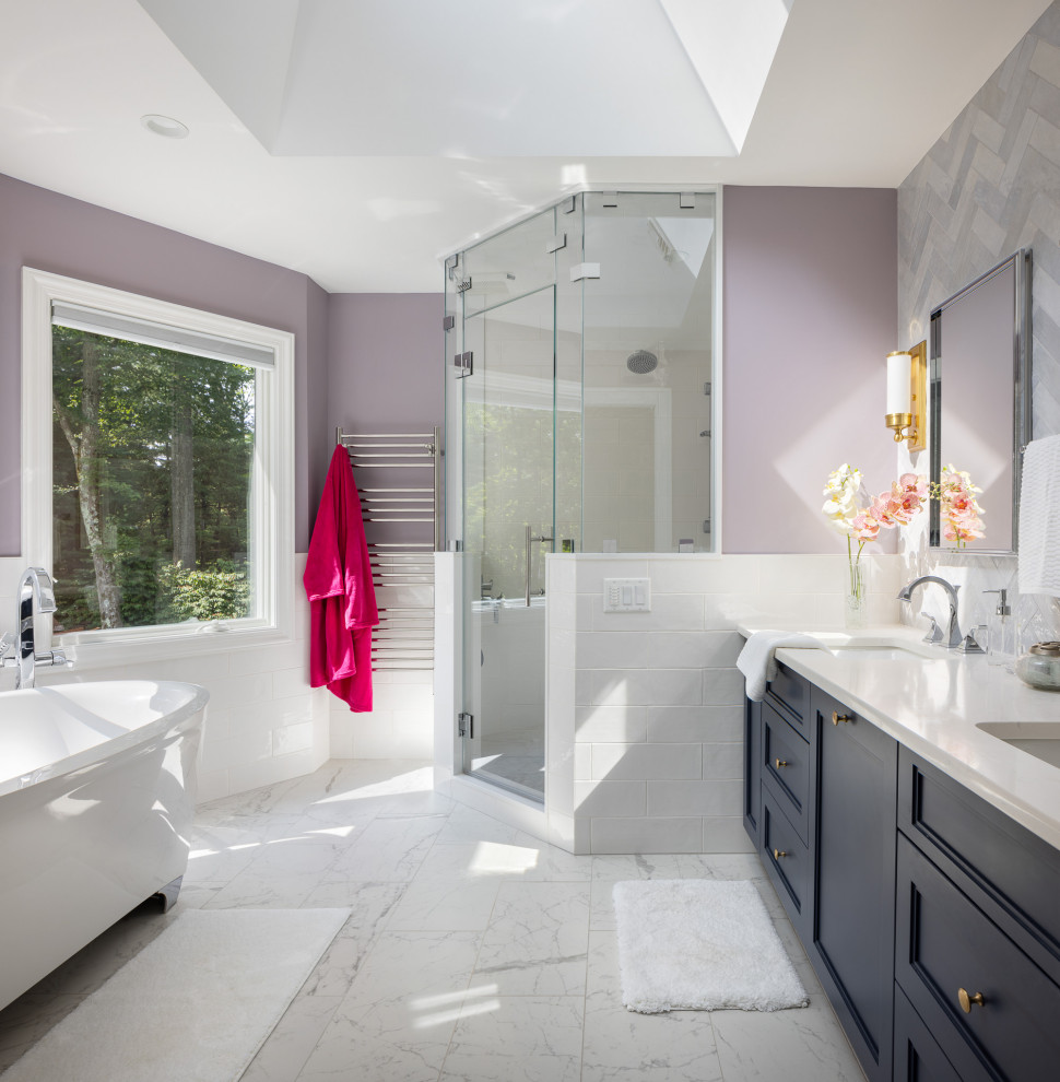 На фото: главная ванная комната среднего размера в стиле неоклассика (современная классика) с фасадами с утопленной филенкой, синими фасадами, отдельно стоящей ванной, угловым душем, биде, разноцветной плиткой, цементной плиткой, фиолетовыми стенами, полом из керамической плитки, врезной раковиной, столешницей из искусственного кварца, белым полом, душем с распашными дверями, белой столешницей, сиденьем для душа, тумбой под две раковины, встроенной тумбой и сводчатым потолком