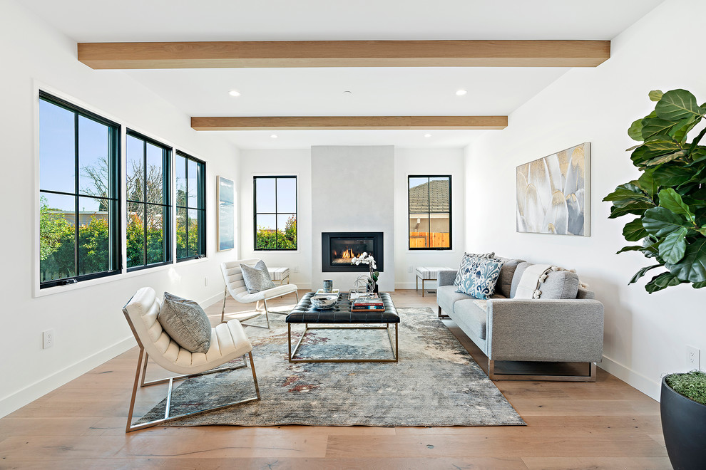 Inspiration for a large transitional open concept family room in San Francisco with a library, white walls, a plaster fireplace surround, no tv, medium hardwood floors, a standard fireplace and brown floor.
