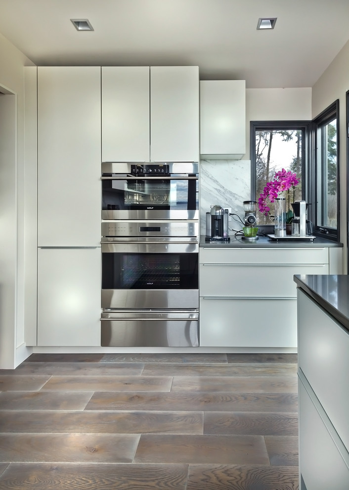 Inspiration for a large contemporary u-shaped kitchen pantry in Minneapolis with an undermount sink, flat-panel cabinets, grey cabinets, quartz benchtops, multi-coloured splashback, stone slab splashback, stainless steel appliances, medium hardwood floors and with island.