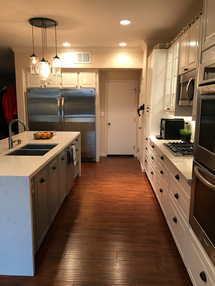 Large country l-shaped eat-in kitchen in San Diego with a double-bowl sink, recessed-panel cabinets, white cabinets, granite benchtops, multi-coloured splashback, matchstick tile splashback, stainless steel appliances, dark hardwood floors, with island and brown floor.