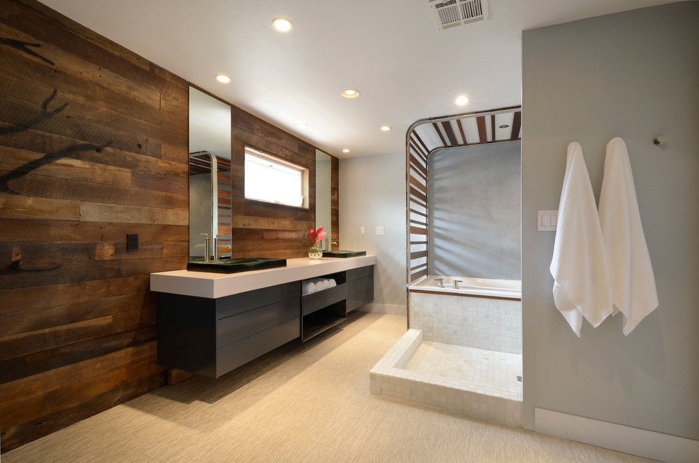Large modern master bathroom in Austin with a vessel sink, flat-panel cabinets, grey cabinets, solid surface benchtops, an undermount tub, an open shower, a wall-mount toilet, white tile and stone tile.