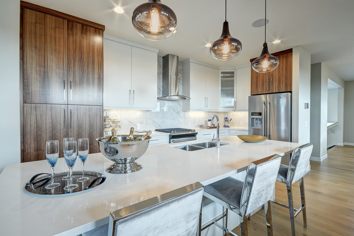 Example of a mid-sized transitional single-wall light wood floor and beige floor enclosed kitchen design in Calgary with an undermount sink, flat-panel cabinets, white cabinets, quartz countertops, white backsplash, stainless steel appliances, an island and marble backsplash