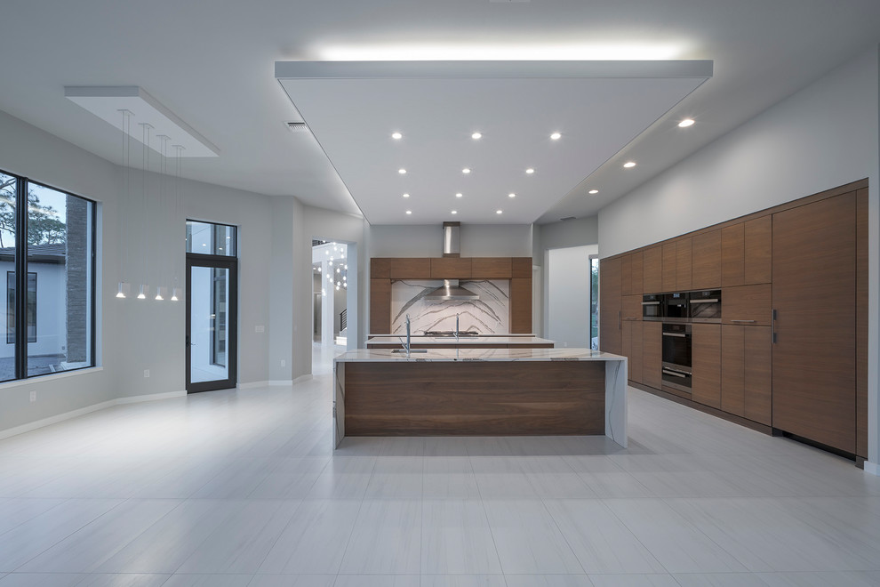Inspiration for an expansive contemporary kitchen in Orlando with an integrated sink, flat-panel cabinets, light wood cabinets, quartzite benchtops, grey splashback, stone slab splashback, black appliances, porcelain floors, multiple islands, grey floor and grey benchtop.