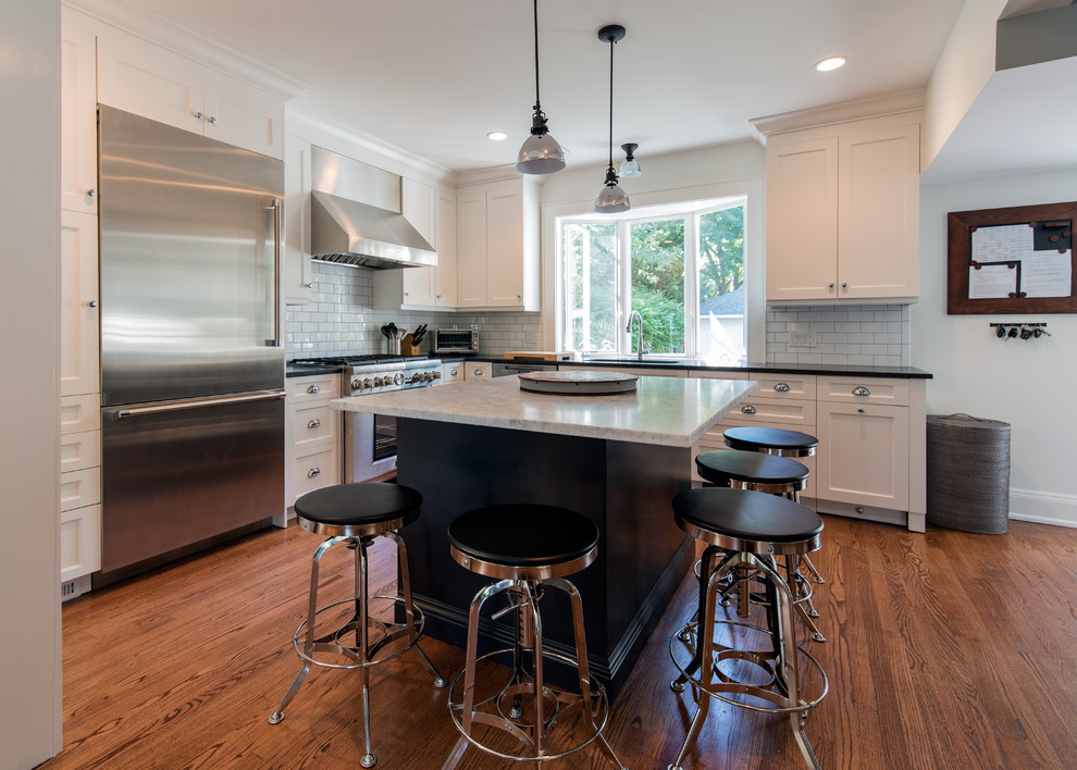 Eat-in kitchen - mid-sized transitional l-shaped medium tone wood floor and brown floor eat-in kitchen idea with an undermount sink, recessed-panel cabinets, white cabinets, quartzite countertops, white backsplash, subway tile backsplash, stainless steel appliances, an island and gray countertops