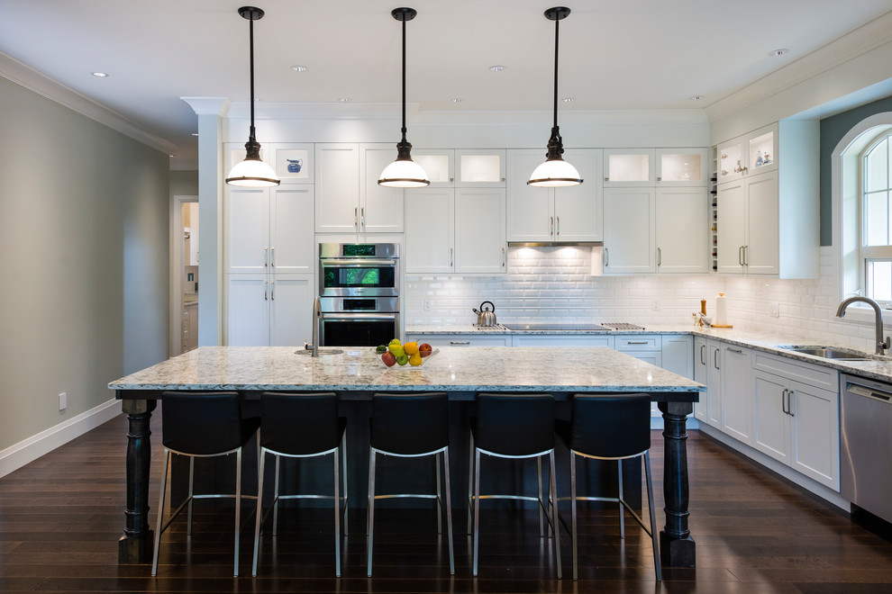 Example of a large transitional l-shaped dark wood floor open concept kitchen design in Vancouver with an undermount sink, shaker cabinets, white cabinets, quartz countertops, white backsplash, subway tile backsplash, stainless steel appliances and an island