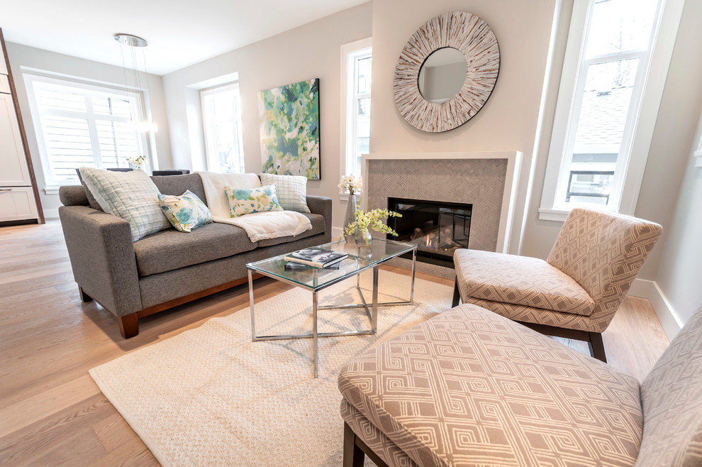 Photo of a mid-sized transitional formal open concept living room in Vancouver with white walls, light hardwood floors, a standard fireplace, a tile fireplace surround and no tv.