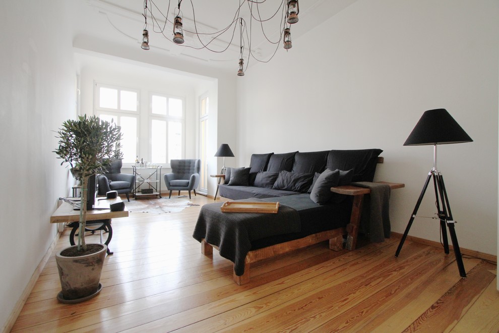 Großes, Abgetrenntes Industrial Wohnzimmer ohne Kamin mit weißer Wandfarbe, braunem Holzboden und freistehendem TV in Berlin