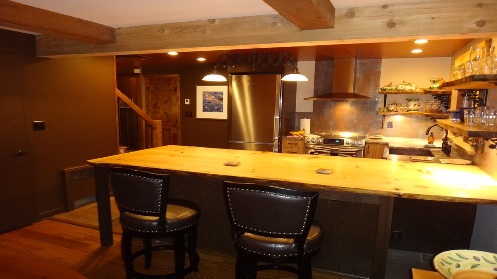 Mid-sized mountain style kitchen photo with medium tone wood cabinets, wood countertops, metallic backsplash and an island