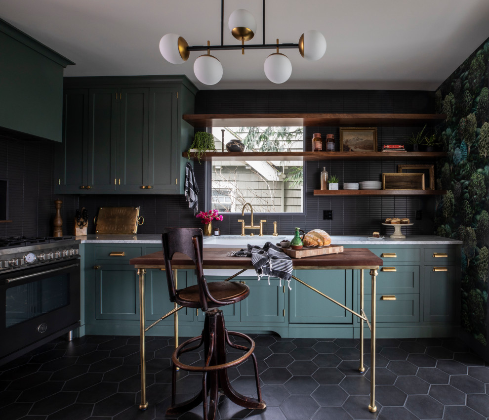 Transitional l-shaped kitchen in Portland with a farmhouse sink, shaker cabinets, green cabinets, black splashback, matchstick tile splashback, black appliances, with island, black floor and white benchtop.