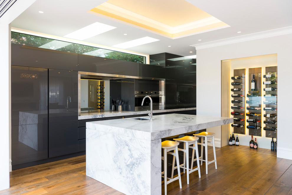 Design ideas for a contemporary galley kitchen in Sydney with an undermount sink, flat-panel cabinets, grey cabinets, stainless steel appliances, medium hardwood floors, with island and brown floor.