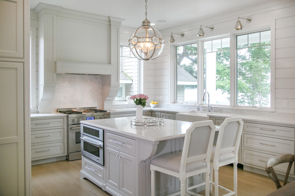 Exempel på ett mellanstort klassiskt vit vitt kök, med en rustik diskho, luckor med profilerade fronter, grå skåp, bänkskiva i kvarts, vitt stänkskydd, integrerade vitvaror, ljust trägolv, en köksö och brunt golv