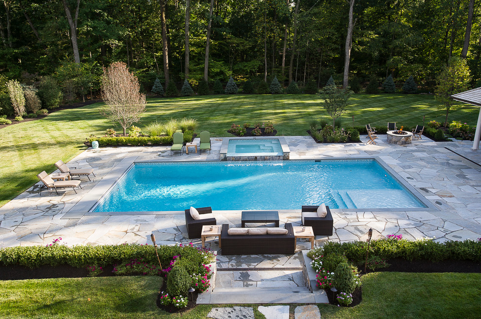 Traditional backyard rectangular natural pool in New York with a hot tub and natural stone pavers.