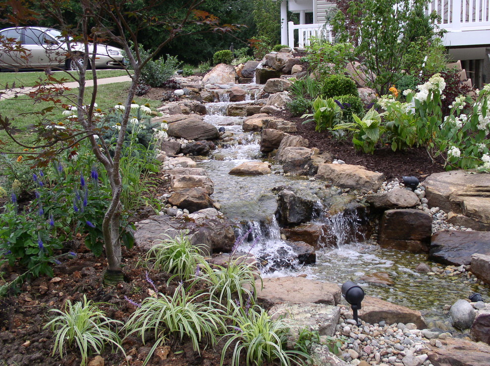Photo of a small tropical sloped shaded garden for summer in Kansas City with mulch and with waterfall.
