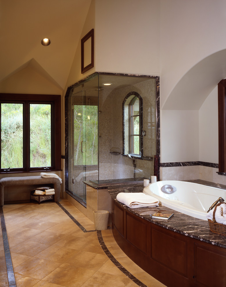 Inspiration for a traditional master bathroom in Denver with an undermount sink, raised-panel cabinets, dark wood cabinets, laminate benchtops, a drop-in tub, a corner shower, a two-piece toilet, beige tile, stone tile, beige walls and travertine floors.