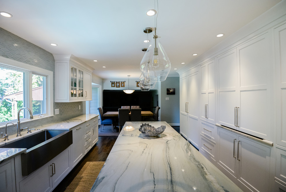 Eat-in kitchen - large transitional u-shaped medium tone wood floor and brown floor eat-in kitchen idea in DC Metro with a farmhouse sink, recessed-panel cabinets, white cabinets, marble countertops, stainless steel appliances, an island, gray backsplash and porcelain backsplash