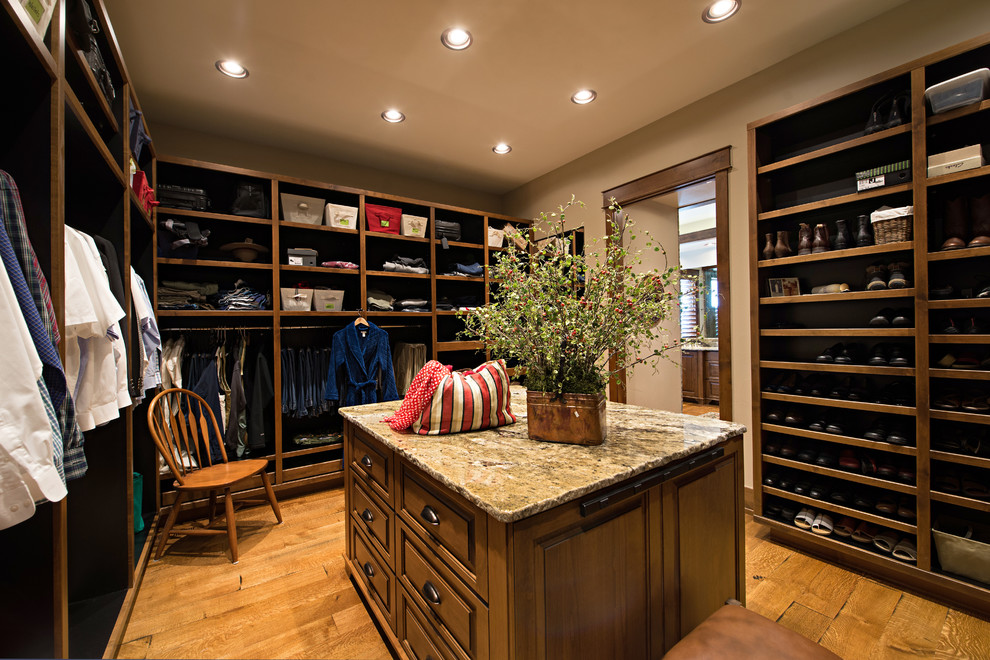This is an example of an expansive arts and crafts gender-neutral walk-in wardrobe in Denver with medium wood cabinets, medium hardwood floors and raised-panel cabinets.