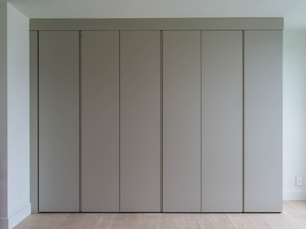 Exemple d'une armoire encastrée tendance neutre avec un placard à porte plane, des portes de placard grises et parquet clair.