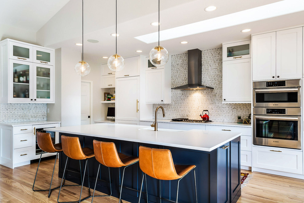 Inspiration for a transitional kitchen in Denver with a farmhouse sink, shaker cabinets, white cabinets, multi-coloured splashback, stainless steel appliances, light hardwood floors and with island.