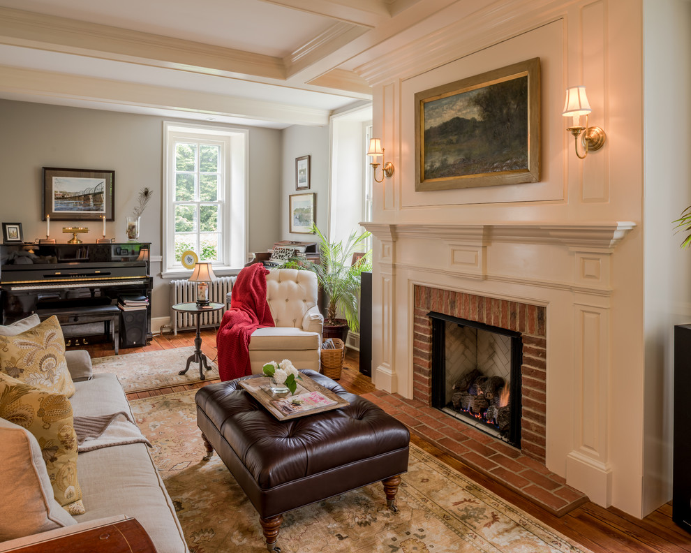 Inspiration for a small traditional enclosed living room in Philadelphia with a music area, grey walls, medium hardwood floors, a standard fireplace, a brick fireplace surround and a concealed tv.