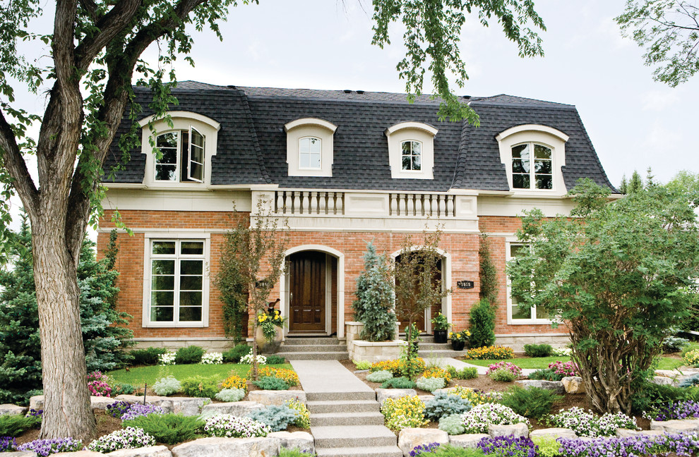 This is an example of a traditional two-storey brick red duplex exterior in Calgary with a shingle roof.