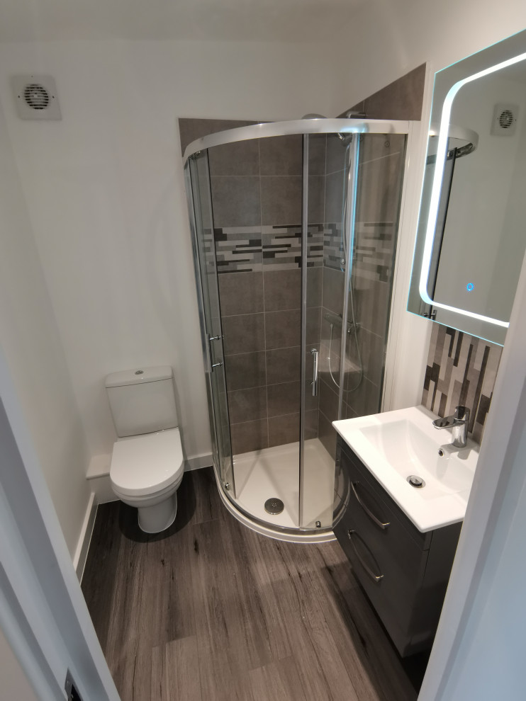 Small modern master bathroom in Cambridgeshire with flat-panel cabinets, grey cabinets, a corner shower, a two-piece toilet, gray tile, ceramic tile, white walls, vinyl floors, a drop-in sink, grey floor, a sliding shower screen, a single vanity, a floating vanity and recessed.
