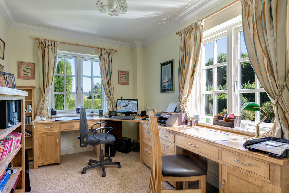 This is an example of a country home office in Devon with yellow walls and a built-in desk.