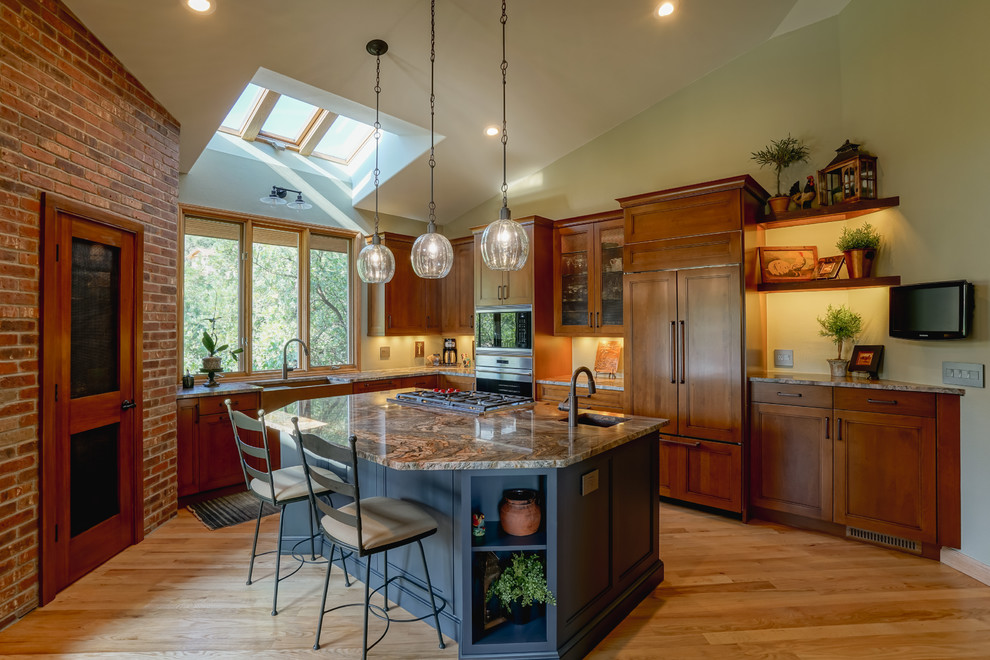 Inspiration for a mid-sized transitional medium tone wood floor and brown floor kitchen remodel in Denver with a farmhouse sink, recessed-panel cabinets, medium tone wood cabinets, granite countertops, paneled appliances and an island