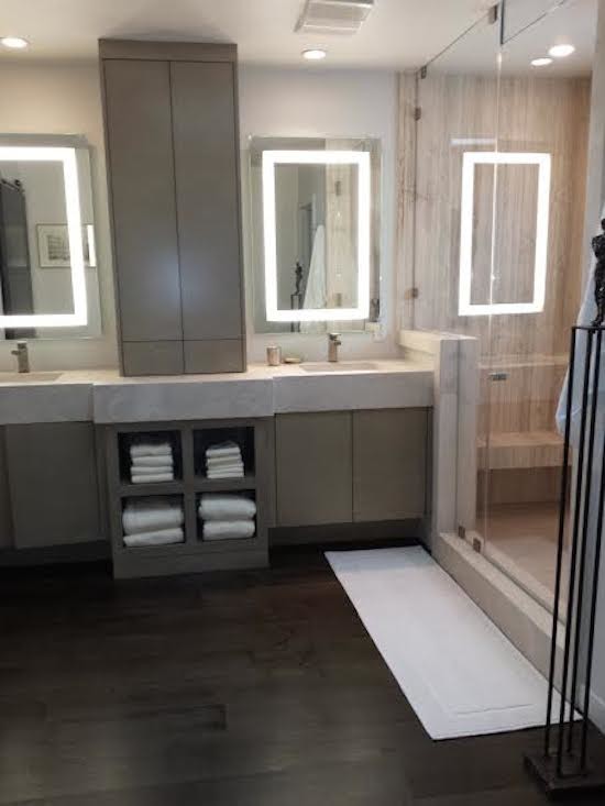 This is an example of a large contemporary master bathroom in Los Angeles with an undermount sink, flat-panel cabinets, solid surface benchtops, a double shower, a one-piece toilet, stone slab and dark hardwood floors.