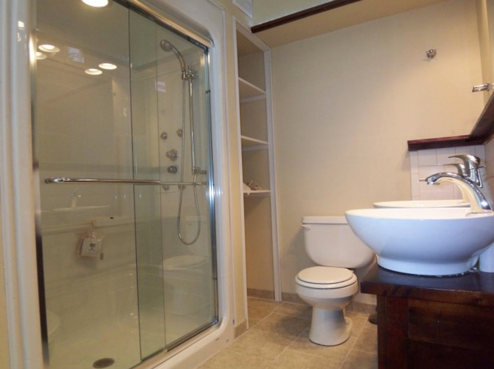 Alcove shower - mid-sized white tile and porcelain tile alcove shower idea in Orange County with a one-piece toilet, beige walls, a vessel sink and wood countertops