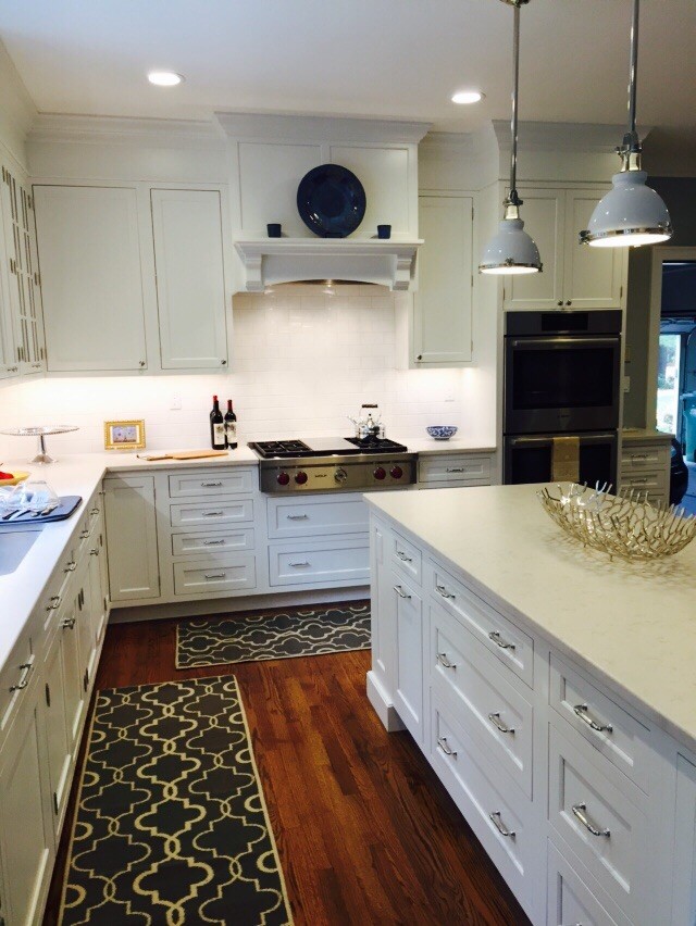 Inspiration for a mid-sized transitional l-shaped medium tone wood floor eat-in kitchen remodel in Bridgeport with an undermount sink, shaker cabinets, white cabinets, solid surface countertops, white backsplash, subway tile backsplash, stainless steel appliances and an island