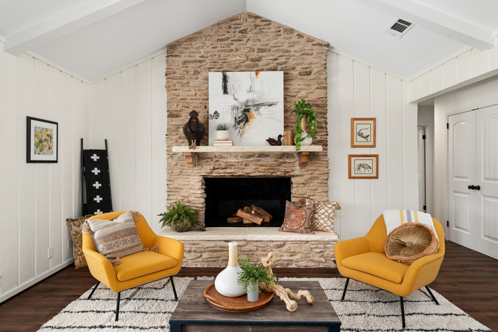 Cette image montre un salon rustique de taille moyenne et fermé avec un mur blanc, un sol en vinyl, un manteau de cheminée en pierre de parement, un sol marron, poutres apparentes et du lambris de bois.