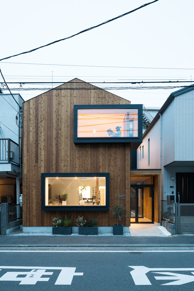Asian two-storey brown house exterior in Yokohama with a metal roof, wood siding and a gable roof.