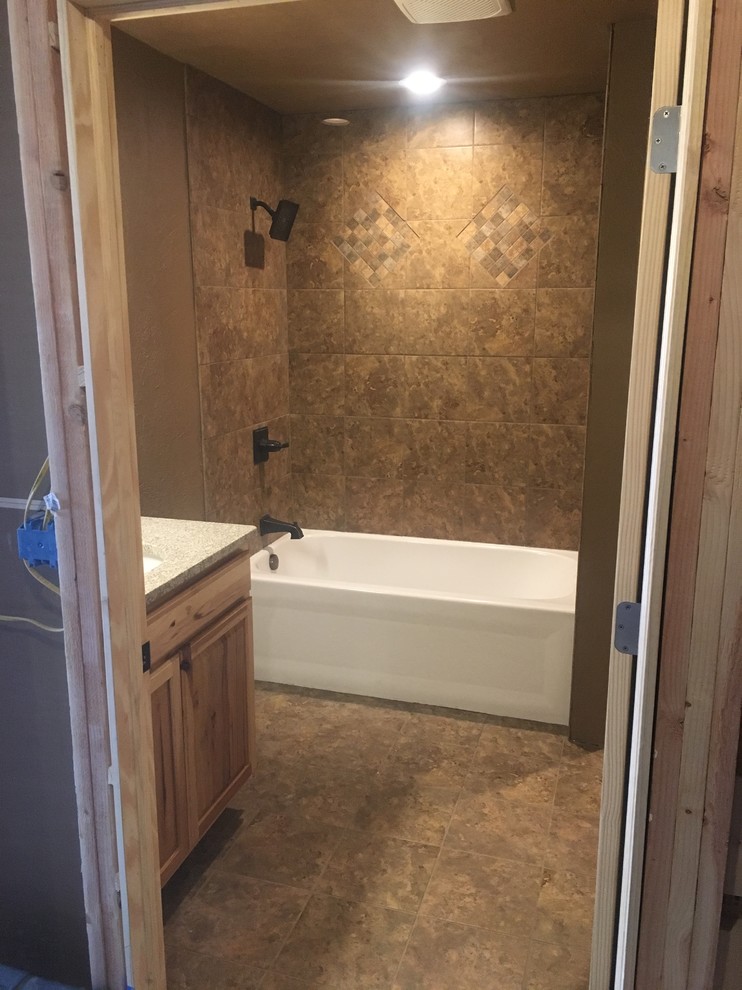 Design ideas for a mid-sized country master bathroom in Other with raised-panel cabinets, light wood cabinets, an alcove tub, a shower/bathtub combo, a two-piece toilet, brown tile, ceramic tile, green walls, ceramic floors, an integrated sink, granite benchtops, brown floor and a shower curtain.