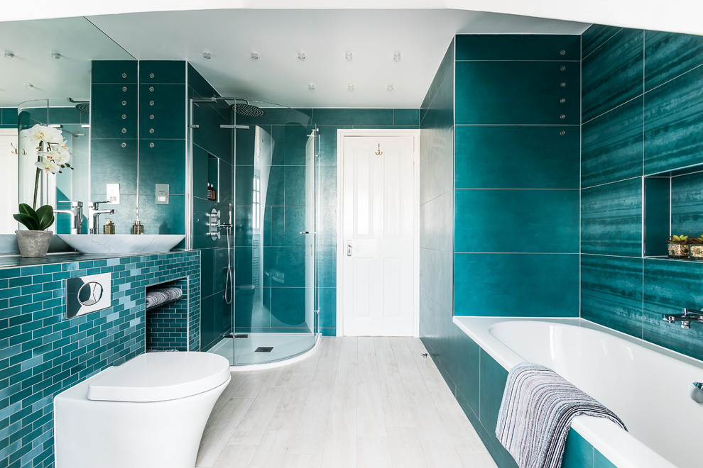 Photo of a contemporary master bathroom in London with a drop-in tub, a corner shower, a wall-mount toilet, green tile, a vessel sink and beige floor.