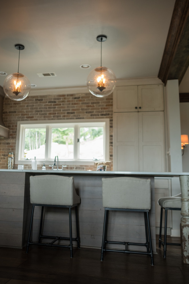 Example of a large transitional galley dark wood floor and brown floor open concept kitchen design with a farmhouse sink, shaker cabinets, quartz countertops, brown backsplash, brick backsplash, stainless steel appliances and an island