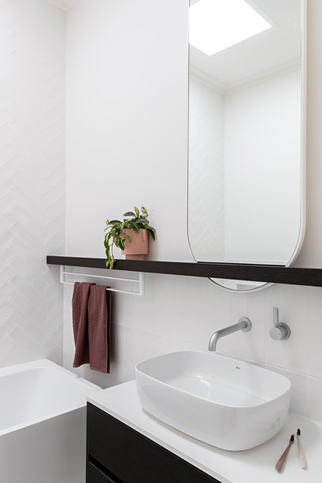 Photo of a contemporary bathroom in Melbourne with flat-panel cabinets, black cabinets, a freestanding tub, white tile, white walls, a vessel sink, white floor, white benchtops, a single vanity and a floating vanity.