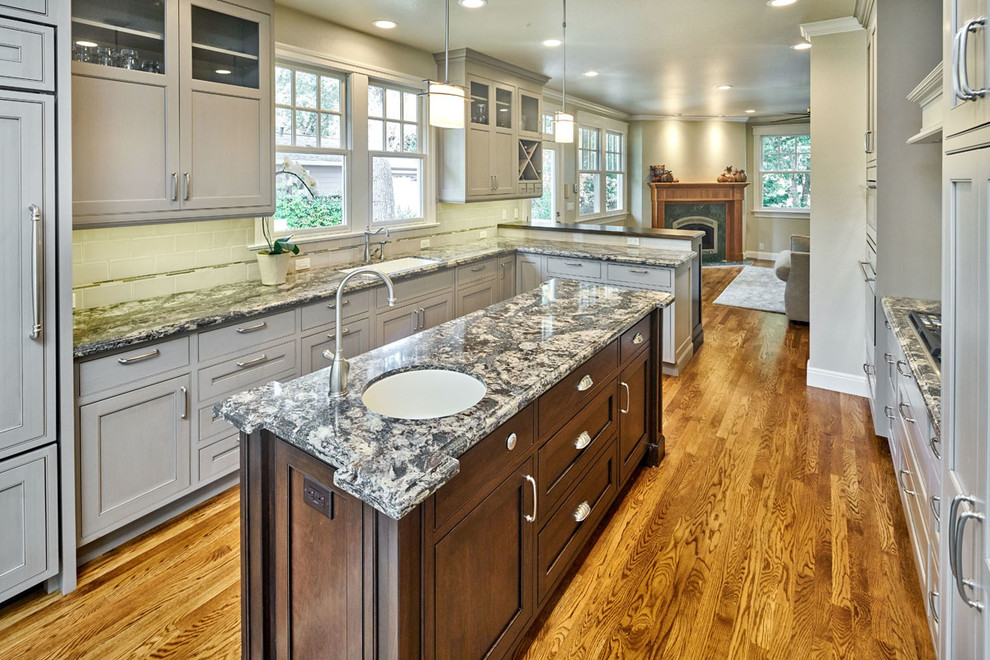 Example of a mid-sized transitional l-shaped medium tone wood floor eat-in kitchen design in San Francisco with an undermount sink, beaded inset cabinets, gray cabinets, quartz countertops, gray backsplash, ceramic backsplash, paneled appliances and an island