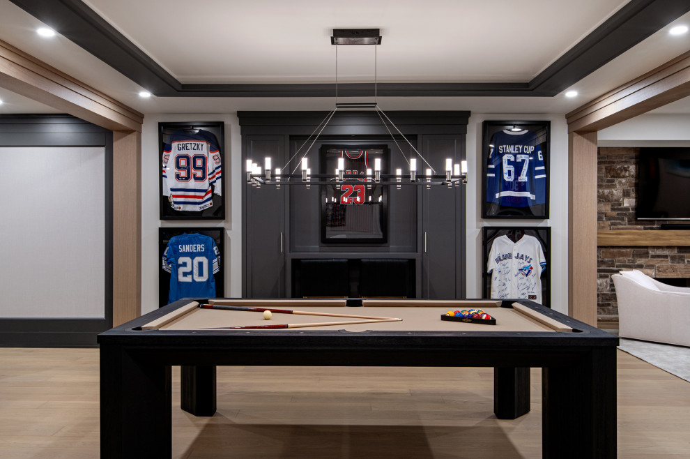 Basement game room - large transitional medium tone wood floor and tray ceiling basement game room idea in Toronto