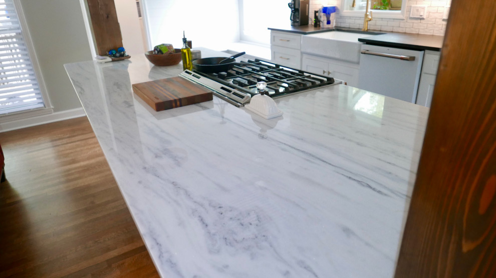 Eat-in kitchen - mid-sized transitional galley porcelain tile and black floor eat-in kitchen idea with a farmhouse sink, shaker cabinets, blue cabinets, marble countertops, white backsplash, subway tile backsplash, white appliances, an island and multicolored countertops