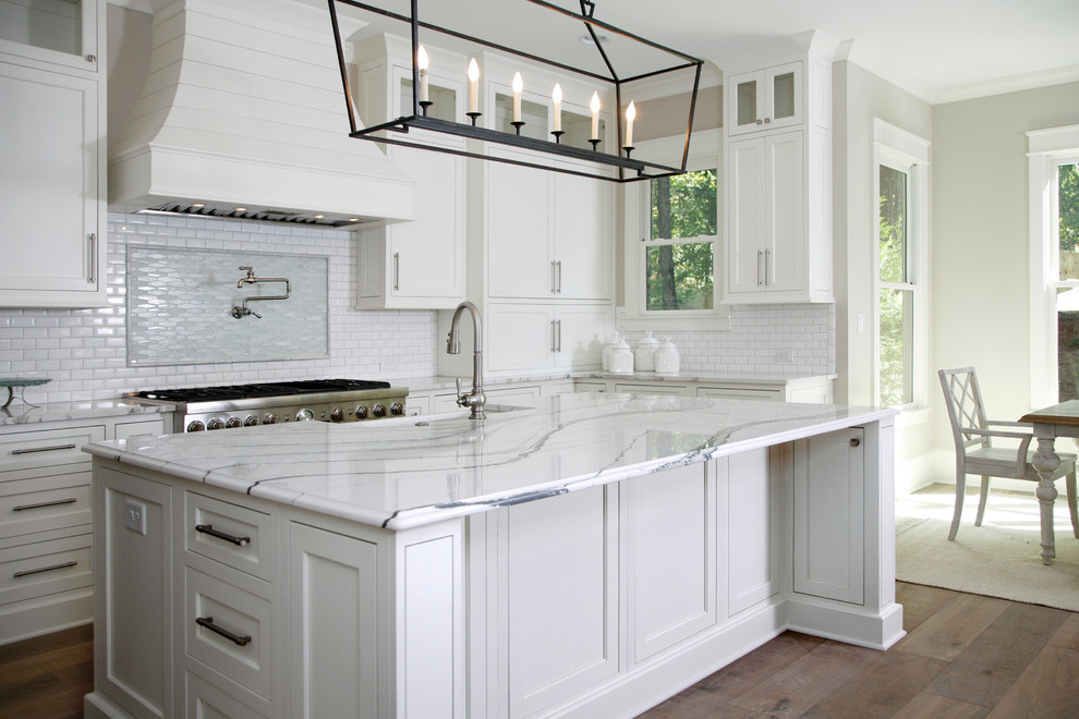 Expansive traditional u-shaped eat-in kitchen in Atlanta with an undermount sink, white cabinets, marble benchtops, white splashback, ceramic splashback, stainless steel appliances, light hardwood floors and with island.