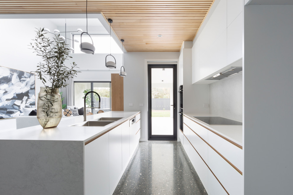 Minimalist concrete floor, gray floor and shiplap ceiling kitchen photo in Canberra - Queanbeyan with a drop-in sink, recessed-panel cabinets, white cabinets, quartz countertops, white backsplash, quartz backsplash, black appliances, an island and white countertops
