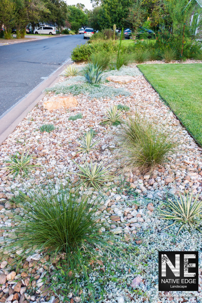Design ideas for a mid-sized front yard full sun xeriscape for summer in Austin with with lawn edging, river rock and a metal fence.