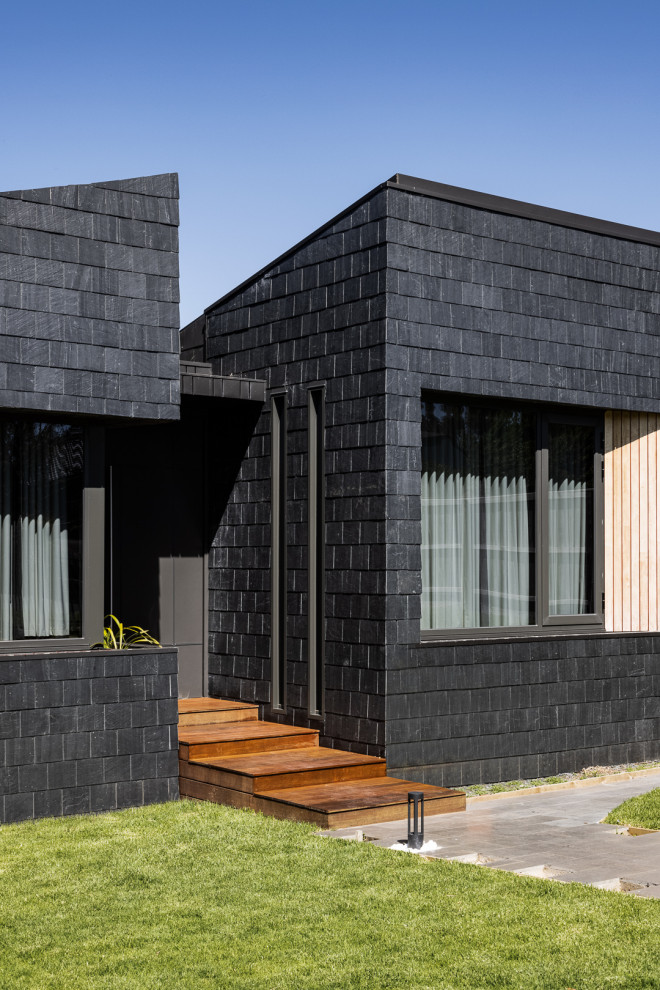 Design ideas for a mid-sized contemporary two-storey grey house exterior in Melbourne with a gable roof, a shingle roof, a black roof and shingle siding.